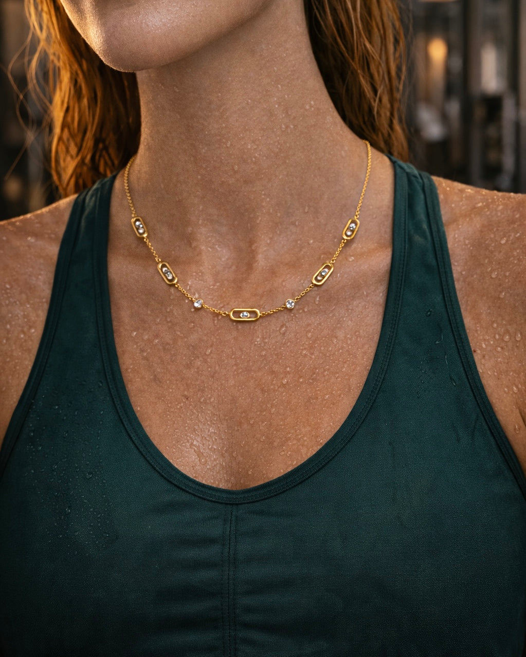 The Glimmer Chain a thin gold chain with small diamond like gems on a model in the gym
