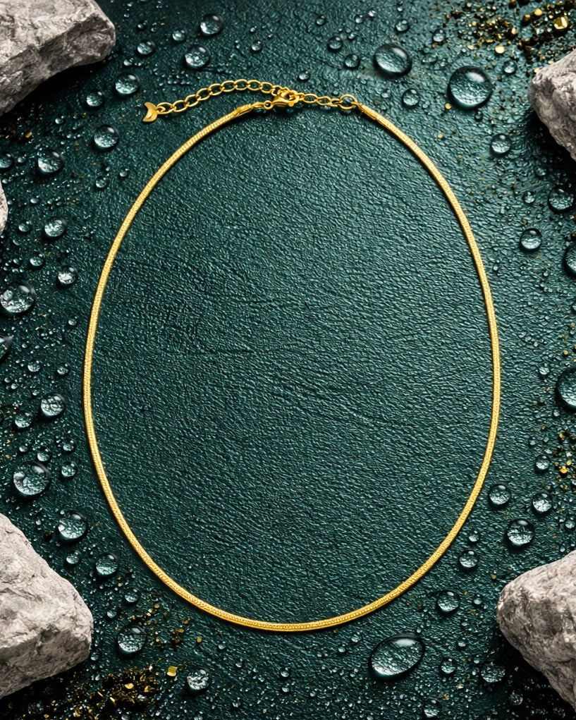 The radiance chain a thin gold cauliflower style chain on a jade green background with earthy elements 